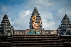 a statue sitting on top of a wooden bench in front of an ornately decorated building