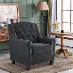 a gray chair sitting on top of a rug next to a table and lamp in a room