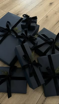 several black wrapped presents on a wooden floor