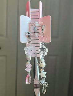 a pink hair comb holder with various beads and charms hanging from it