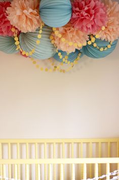 there is a crib in the room with paper flowers on it and balls hanging from the ceiling