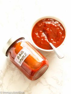 two jars of sauce sitting on top of a table