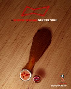 a wooden spoon with some food in it next to a cup on the floor that says love for the beer