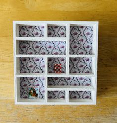 a small white shelf with several different designs on the top and bottom, sitting on a wooden surface