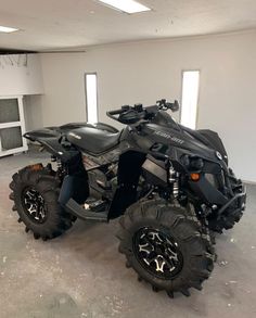 a black four - wheeler is parked in a large room with several tires on it