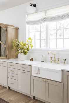 a large kitchen with white cabinets and wooden floors is pictured in this image, there are two windows above the sink