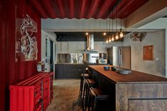 a kitchen with red walls and wooden counter tops next to an island in the middle