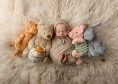 a baby is sleeping next to stuffed animals on a fluffy white blanket with a teddy bear