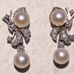 The 182nd Street: Hollywood Glam Era Pearl And Diamond Dangler Earrings. The Earrings Each Feature An Akoya Cultured Pearl Dangling With A Round Brilliant Cut Natural Diamond At The Bottom. Above Is A Bow Motif Set With Transitional Round Brilliant Cut Natural Diamonds With An Additional Akoya Pearl. The Diamonds Have An Approximate Total Weight By Measurement Of 0.52 Carats. The Pearls Have A Measurement Of 7.5 Millimeters. The Earrings Are Finished With Posts And Push Style Backs And Are Crafted In 14 Karat White Gold, Measuring Just Under 1.25 Inches In Total Length. White Clip-on Pearl Earrings For Evening, Luxury Platinum Pearl Earrings For Formal Occasions, Elegant Diamond White Clip-on Jewelry, Classic White Gold Pearl Earrings, Classic Platinum Pearl Earrings For Formal Occasions, Luxury White Clip-on Diamond Earrings, Elegant Formal Clip-on Diamond Earrings, Formal Bridal Diamond Clip-on Earrings, Elegant Bridal Earrings In Diamond White For Formal Occasions