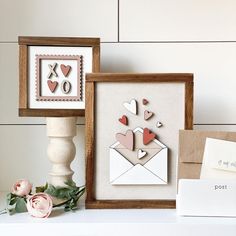 two framed pictures with hearts on them next to a vase and flower arrangement in front of a white wall