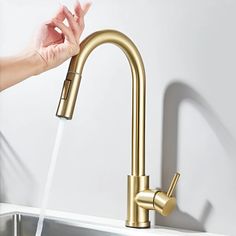 a person's hand is holding the faucet in front of a sink