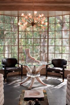 a living room filled with furniture and a chandelier above a glass top table