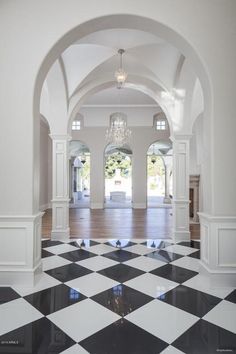 an empty room with black and white checkered floor, chandelier and windows