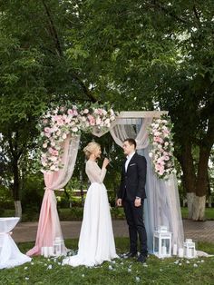 a bride and groom standing under an arch with flowers on it at their wedding ceremony