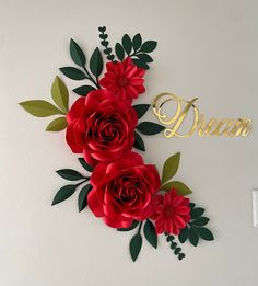 paper flowers are arranged on the wall with gold lettering