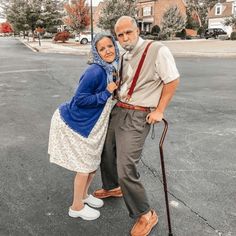 an older man and woman standing in the middle of a parking lot with their canes