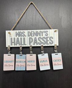 three name tags hang from a rope on a black board with the words, mrs denny's hall passes