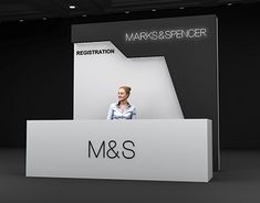 a woman standing behind a large white sign with the word m & s on it