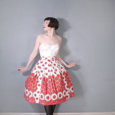 Fantastic and so romantic 50s vivid red floral skirt in white cotton. Lovely border design with smaller scattered flowers to the upper skirt and a thicker border pattern which feature small framed floral designs towards the hem. Small vertical panels have been sewn in to create a contrasting effect, very clever! High fitted waist band with button and metal zip fastening. Full fit with box pleats. Light cotton. Midi length. No labels. Skirt is pictured with a petticoat which is not included in th Vintage Red Fitted Petticoat, Fitted Red Petticoat For Spring, Vintage White Gathered Skirt, White Vintage Gathered Skirt, White Vintage Skirt With Gathered Detail, Vintage White Pleated Skirt, Spring Retro Petticoat, White Full Skirt For Garden Party, White Retro Full Skirt