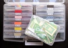 several clear storage containers with different colored tape in them on a black surface, one is open and the other is closed