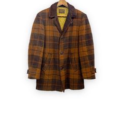 "Step into timeless sophistication with this vintage men's Pendleton wool brown plaid coat. Crafted with premium wool, fully lined for aded comfort and warmth, and featuring a faux fur collar. Retro elegance and exceptional quality, perfect for any occasion. * Brand: Pendleton * Material: Wool * Color: Chocolate brown, nut brown plaid * Size: L * Length: 33\" (top of collar to hem) * Chest: 22\" (measurement taken from flat garment) * Waist: 21\" (measurement taken from flat garment) * Sleeve: 24 1/4\"  * One button on each sleeve, and three buttons on front * Fully lined * 2 side pockets, lined * Inside cuff of each sleeve has wear (see photo 7)  * Faux fur collar has wear (see photo 6) * No moth holes noted  * Age is estimate only * Vintage hanger is for display purposes only and is not Brown Single-breasted Wool Coat, Brown Tweed Wool Coat For Business, Brown Tweed Wool Long Coat, Brown Tweed Long Wool Coat, Brown Long Sport Coat With Button Closure, Winter Tailoring Brown Outerwear, Brown Wool Coat For Winter Tailoring, Brown Wool Single-breasted Outerwear, Classic Brown Long Tweed Jacket