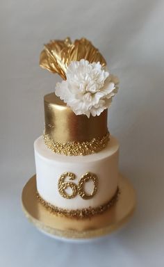 a three tiered cake with gold and white flowers on it's top layer