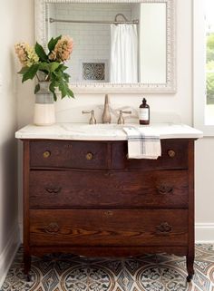 a bathroom with a sink, mirror and flowers on the counter in front of it