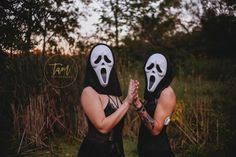 two people with masks on their faces are praying in front of some trees and grass