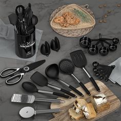 an assortment of kitchen utensils on a cutting board next to bread and coffee mugs