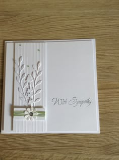 a white card with a flower and ribbon on it