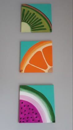 three pieces of fruit painted on canvases in different colors and shapes, each with a slice of watermelon