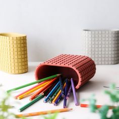 there are many colored pencils in the holder on the table next to each other