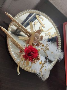 a decorative paper plate with flowers and feathers on the table next to a red book