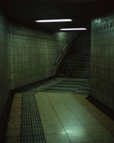 an empty hallway with stairs and tiled floors