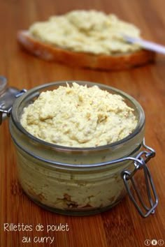 a glass jar filled with food sitting on top of a wooden table next to a spoon