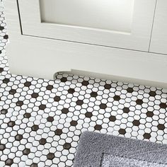 a bathroom with black and white hexagonal tiles on the floor next to a door