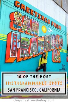 a woman standing in front of a colorful wall with the words greetings from san francisco on it