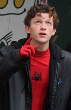 a young man in a red spider suit is making a funny face with his hands