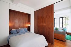 a bed sitting in a bedroom next to a wooden headboard and window sill