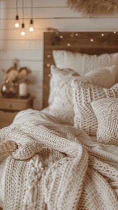 an unmade bed with white blankets and lights