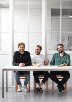 three men sitting at a table in an office