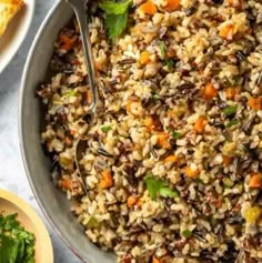 a bowl filled with rice, carrots and parsley on top of a table