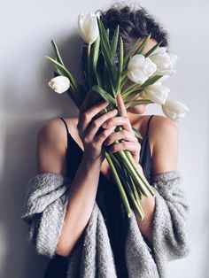 a woman covering her face with flowers