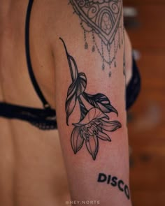 a close up of a person's arm with a flower tattoo on the left shoulder