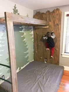 a young boy climbing up the side of a bunk bed in a room with wood floors