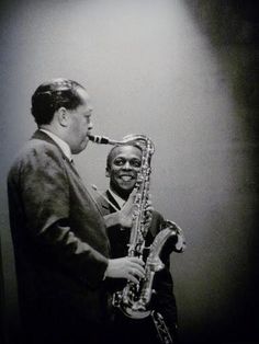 a man standing next to another man holding a saxophone