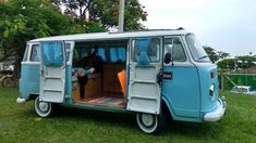 an old blue and white van is parked in the grass with its door open to let people inside