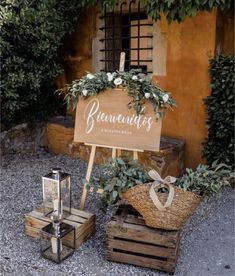 a wooden sign sitting on top of a table next to some crates filled with plants