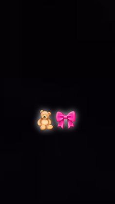 two teddy bears with pink bows in the dark