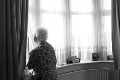 an older woman standing in front of a window